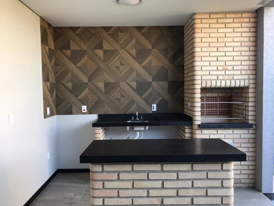 Churrasqueira de tijolinho à vista com bancada em granito preto em área gourmet